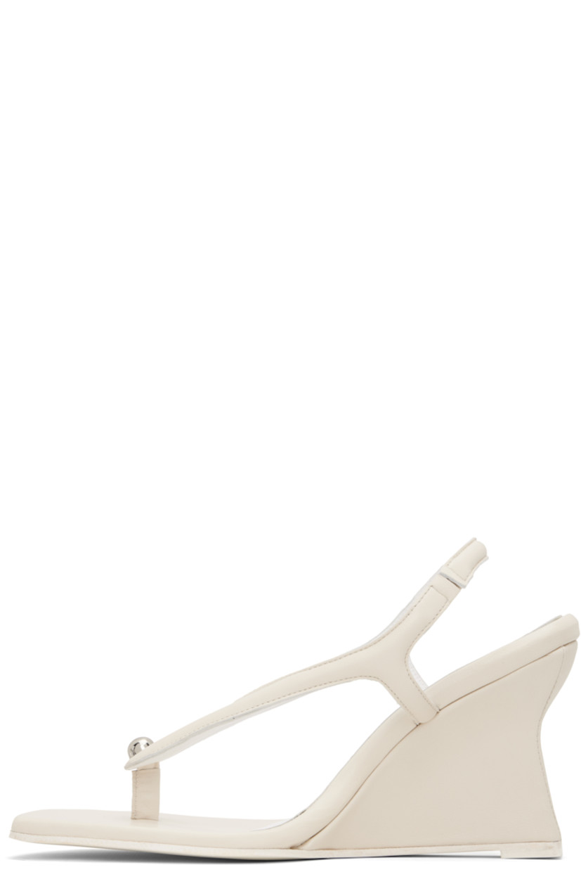 Buffed leather heeled sandals in off-white.

· Open pointed toe
· Thong-style strap and stud at vamp
· Partially elasticized slingback strap
· Logo embossed at padded footbed
· Covered wedge heel with rubber injection
· Leather sole
· Heel: H3.5"

Supplier color: Cream