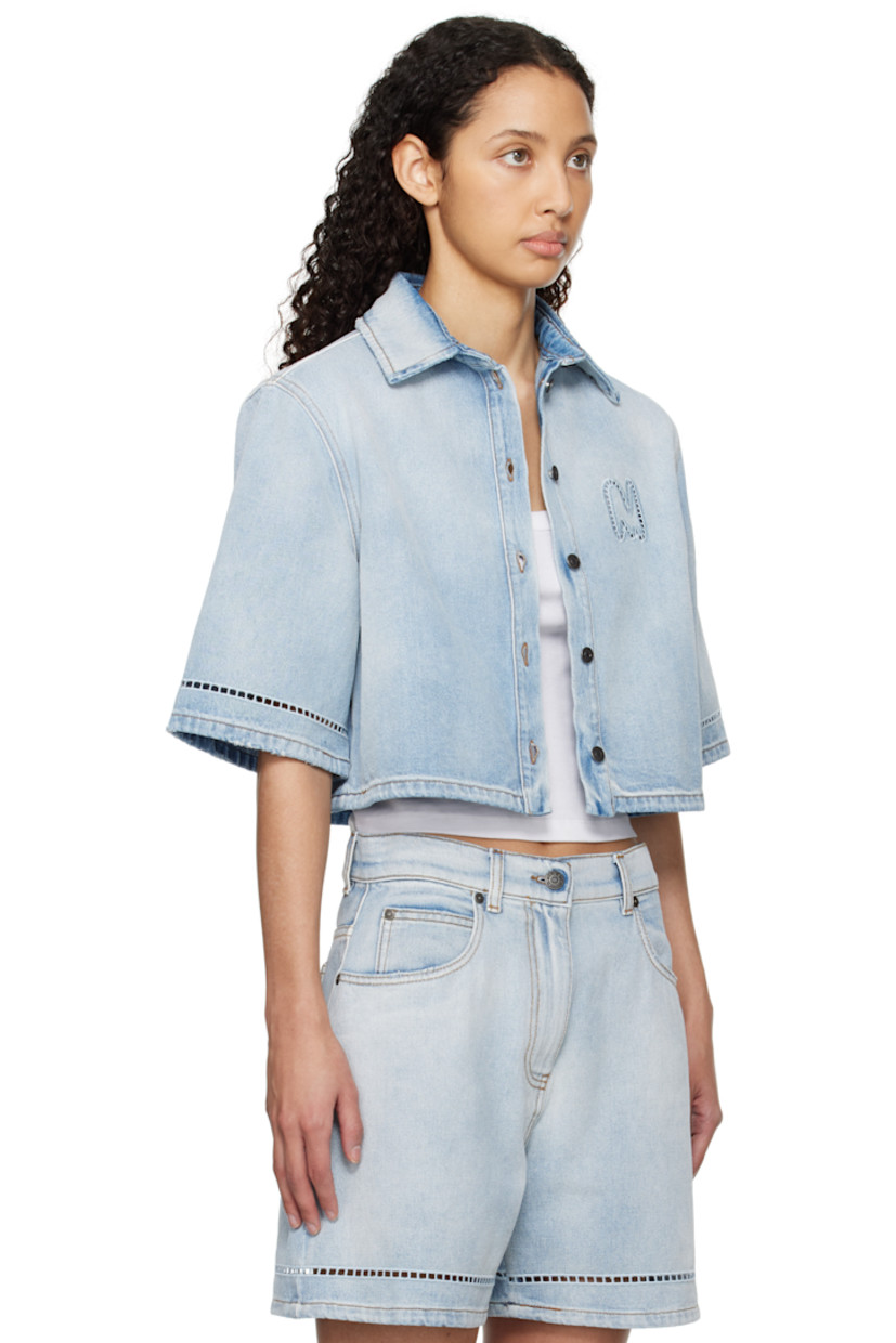 Washed non-stretch denim shirt. Fading and subtle distressing throughout. 

· Spread collar
· Button closure
· Broderie anglaise logo at chest 
· Broderie anglaise detailing at sleeves
· Contrast stitching in brown 

Supplier color: Light blue