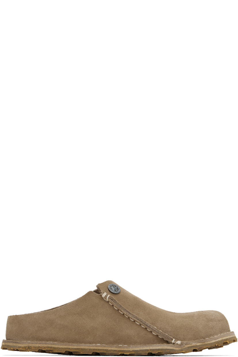 Suede slip-on loafers in beige.

· Logo hardware at vamp
· Pinched seam at outer side
· Logo embossed at inner side
· Logo printed at molded suede footbed
· Cork-latex midsole
· Treaded rubber sole
· Contrast stitching in white

Supplier color: Gray taupe