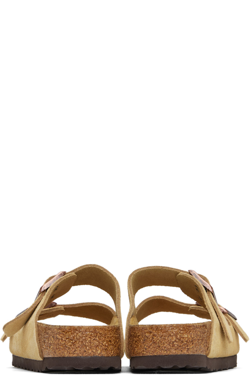 Suede slip-on sandals in beige. 

· Open toe
· Pin-buckle straps at vamp
· Logo embossed at inner side
· Logo printed at molded footbed
· Suede lining
· Cork-latex midsole
· Treaded rubber sole
· Logo-engraved antiqued brass-tone hardware

Supplier color: Latte cream