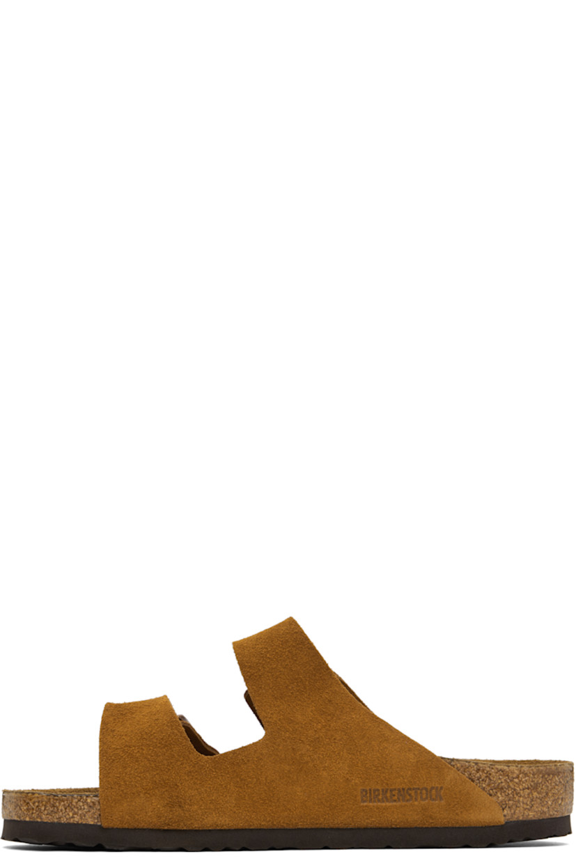 Suede slip-on sandals in tan.

· Adjustable pin-buckle straps at vamp
· Logo embossed at inner side
· Logo stamp at molded suede footbed
· Cork midsole
· Treaded rubber sole
· Logo-engraved antiqued copper-tone hardware

Supplier color: Mink
