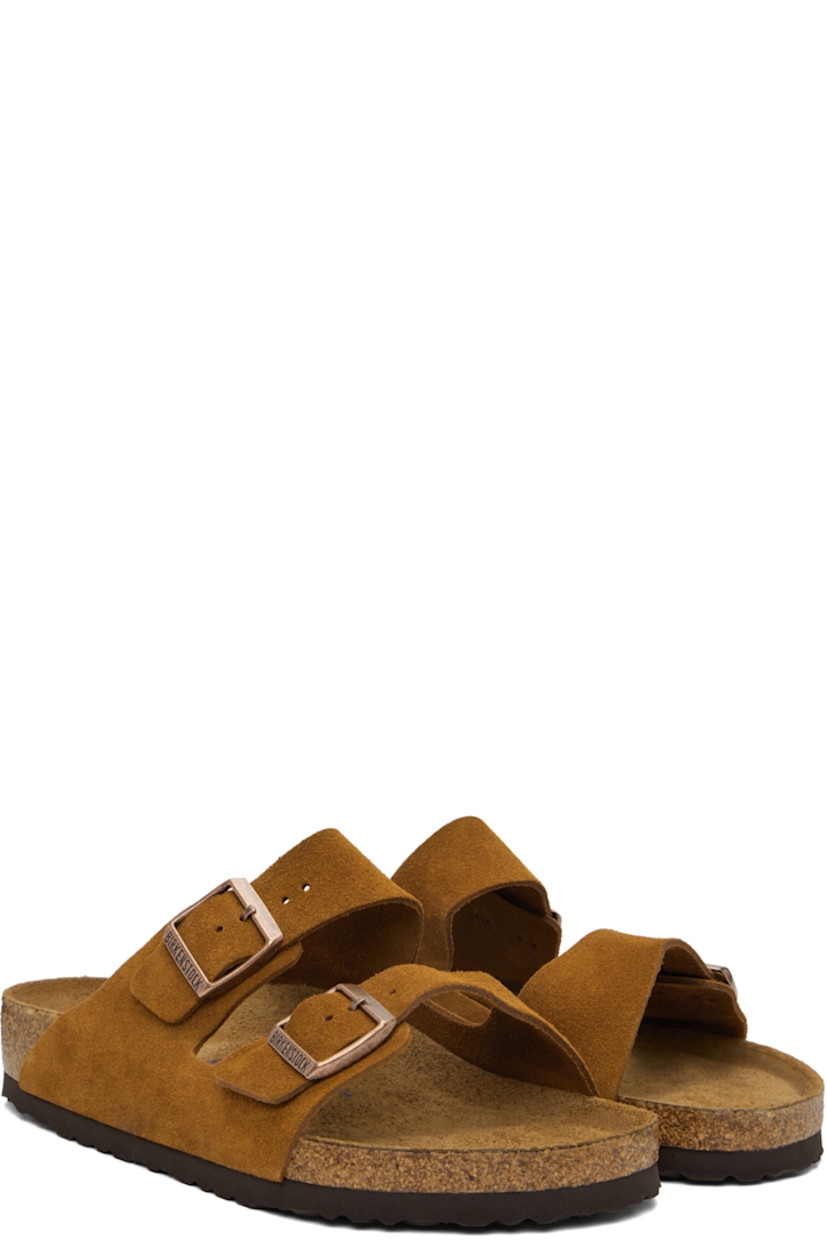 Suede slip-on sandals in tan.

· Adjustable pin-buckle straps at vamp
· Logo embossed at inner side
· Logo stamp at molded suede footbed
· Cork midsole
· Treaded rubber sole
· Logo-engraved antiqued copper-tone hardware

Supplier color: Mink