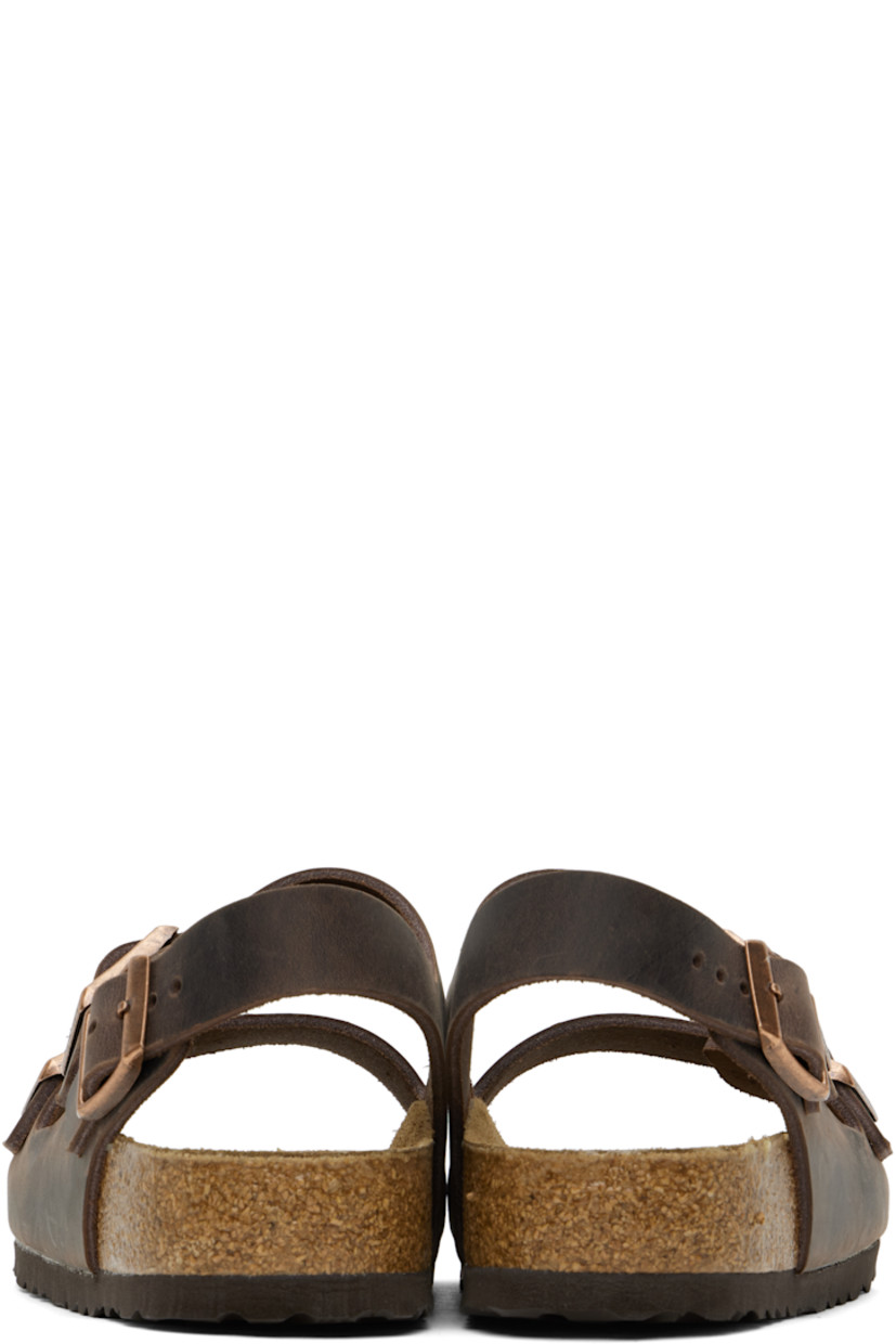Handcrafted oiled nubuck flat sandals in brown.

· Fading throughout
· Open toe
· Adjustable pin-buckle straps at vamp
· Adjustable pin-buckle ankle strap
· Logo embossed at inner side
· Logo printed at molded suede footbed
· Cork midsole
· Treaded rubber sole
· Logo-engraved copper-tone hardware

Supplier color: Habana