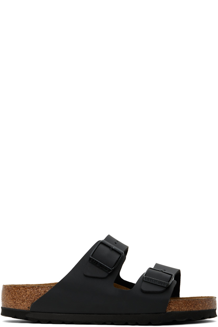 Buffed Birko-Flor® faux-leather slip-on sandals in black.

· Open toe
· Pin-buckle straps at vamp
· Logo embossed at inner side
· Logo printed at molded suede footbed
· Felted lining
· Cork midsole
· Treaded rubber sole

Supplier color: Black