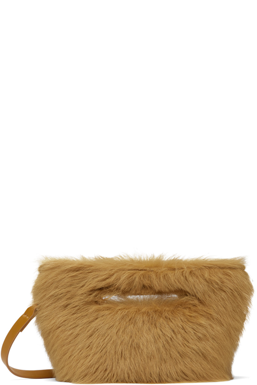 Shearling top handle bag in tan.

· Integrated carry handles
· Detachable crossbody strap
· Logo-engraved bumper studs at base
· Magnetic fastening at throat
· Buffed leather lining
· H6" x W10" x D6"

Supplier color: Caramel