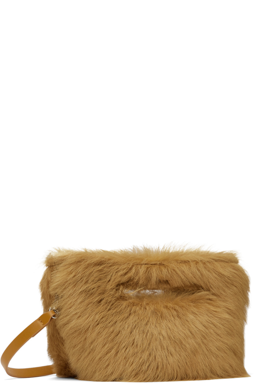 Shearling top handle bag in tan.

· Integrated carry handles
· Detachable crossbody strap
· Logo-engraved bumper studs at base
· Magnetic fastening at throat
· Buffed leather lining
· H6" x W10" x D6"

Supplier color: Caramel