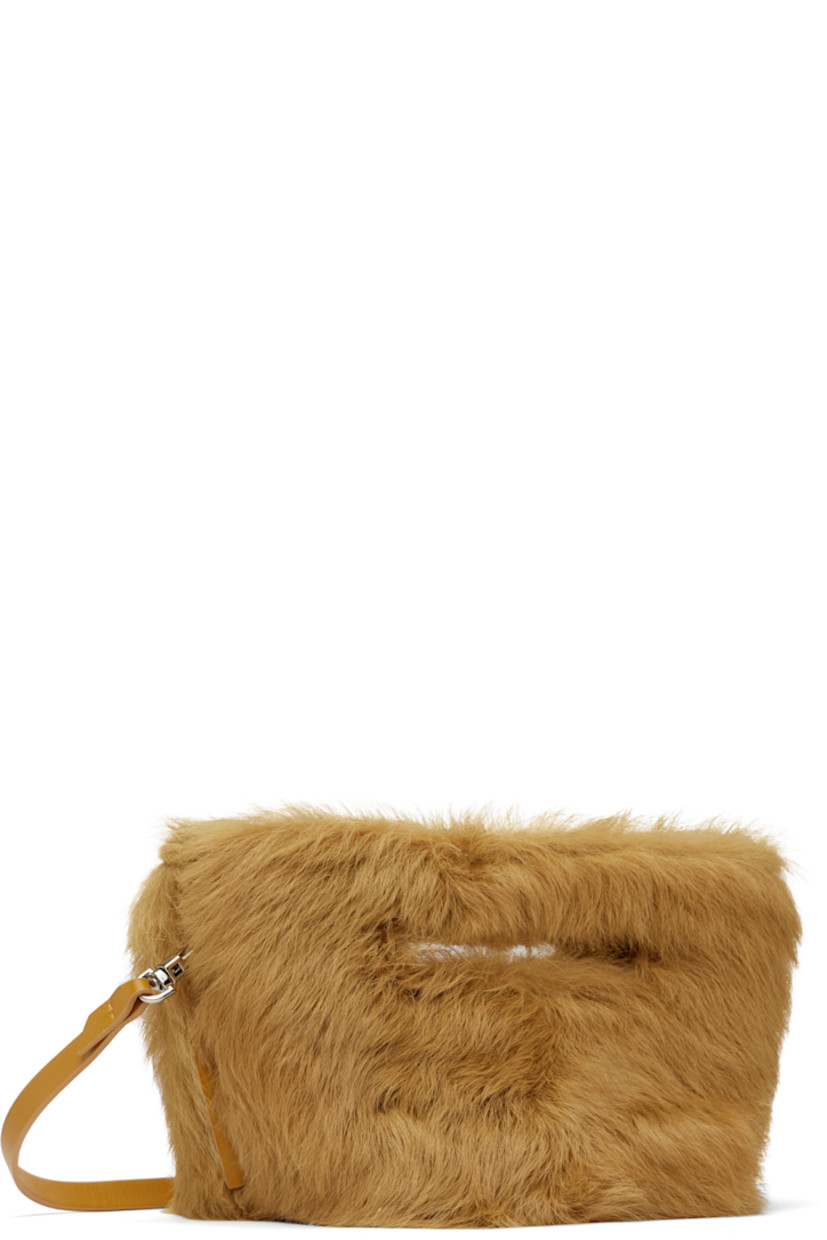 Shearling top handle bag in tan.

· Integrated carry handles
· Detachable crossbody strap
· Logo-engraved bumper studs at base
· Magnetic fastening at throat
· Buffed leather lining
· H6" x W10" x D6"

Supplier color: Caramel