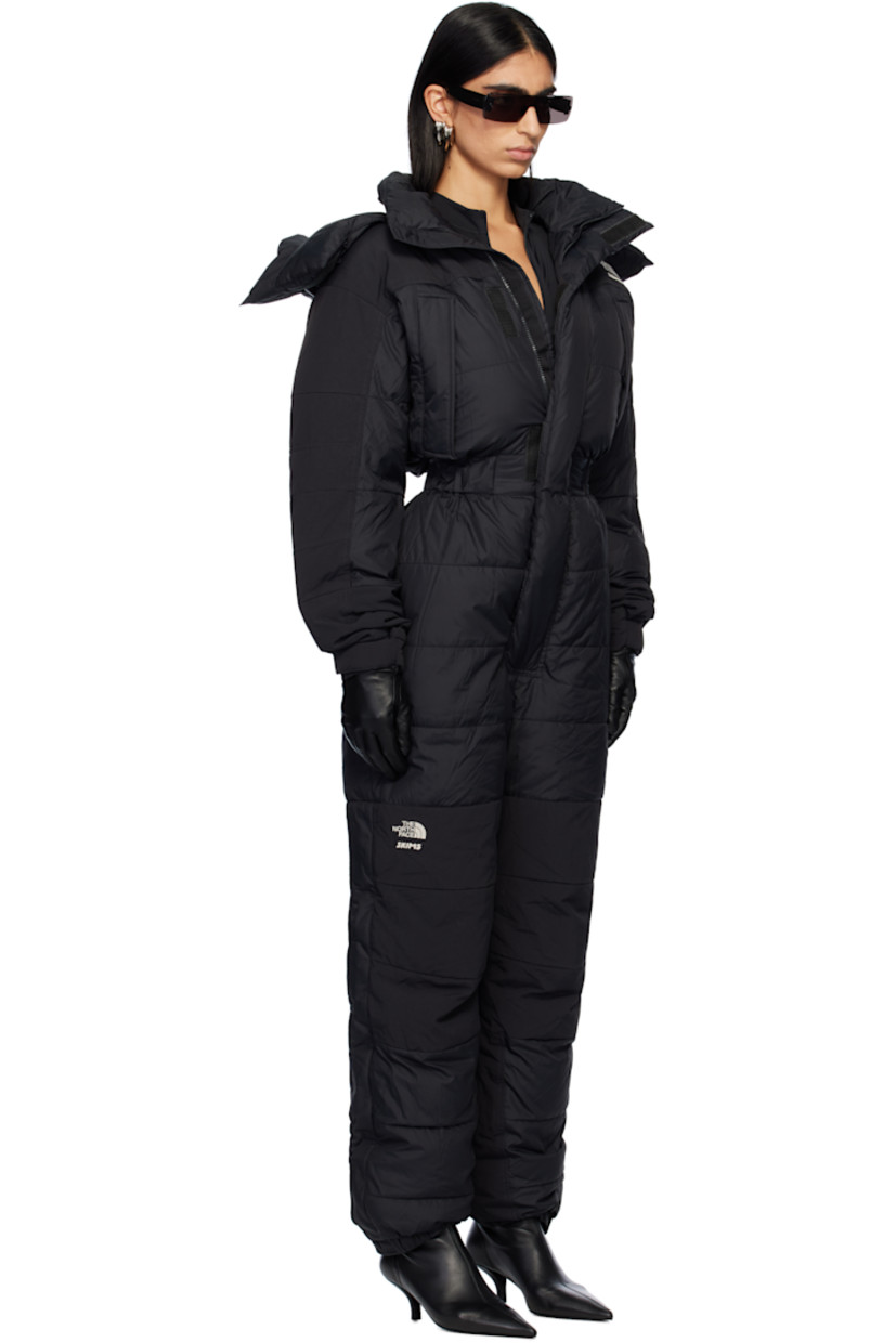 Down-filled and quilted nylon taffeta snow suit.

· Bungee-style drawstring at detachable hood 
· Funnel neck
· Concealed zip closure and velcro placket
· Logo embroidered at chest, leg, and back
· Zip pockets
· Elasticized waist
· Press-stud tabs at elasticized hem 
· Concealed zip vent at outseams
· Text embroidered at sleeve
· Velcro tab at cuffs
· Fully lined

Part of The North Face x SKIMS collaboration.

Available exclusively at SSENSE.

Supplier color: Onyx

Fill: 85% down, 15% waterfowl feathers.