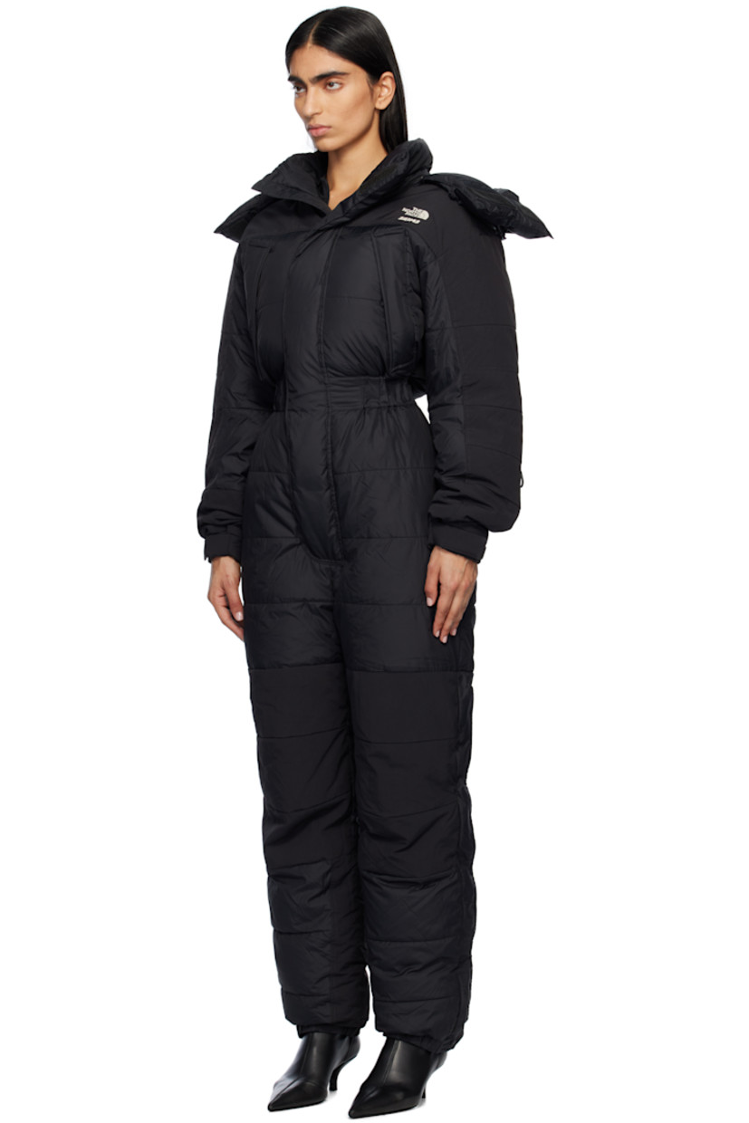 Down-filled and quilted nylon taffeta snow suit.

· Bungee-style drawstring at detachable hood 
· Funnel neck
· Concealed zip closure and velcro placket
· Logo embroidered at chest, leg, and back
· Zip pockets
· Elasticized waist
· Press-stud tabs at elasticized hem 
· Concealed zip vent at outseams
· Text embroidered at sleeve
· Velcro tab at cuffs
· Fully lined

Part of The North Face x SKIMS collaboration.

Available exclusively at SSENSE.

Supplier color: Onyx

Fill: 85% down, 15% waterfowl feathers.