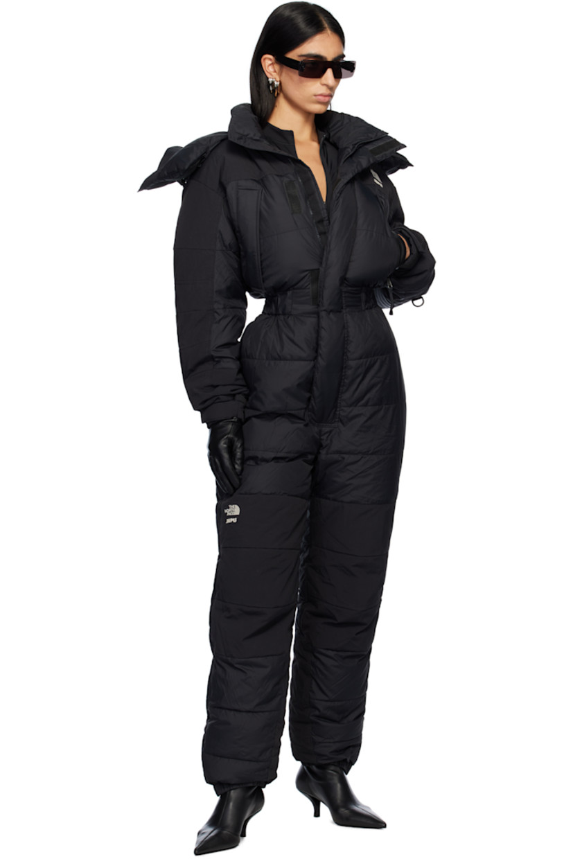 Down-filled and quilted nylon taffeta snow suit.

· Bungee-style drawstring at detachable hood 
· Funnel neck
· Concealed zip closure and velcro placket
· Logo embroidered at chest, leg, and back
· Zip pockets
· Elasticized waist
· Press-stud tabs at elasticized hem 
· Concealed zip vent at outseams
· Text embroidered at sleeve
· Velcro tab at cuffs
· Fully lined

Part of The North Face x SKIMS collaboration.

Available exclusively at SSENSE.

Supplier color: Onyx

Fill: 85% down, 15% waterfowl feathers.