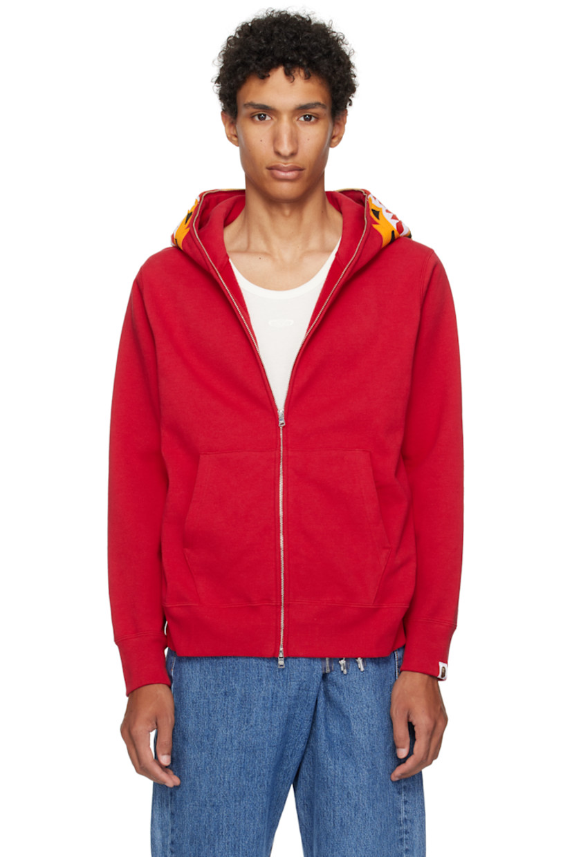 Cotton fleece hoodie. 

· Graphic patches and embroidered text at hood
· Graphics printed at hood and sleeves
· Two-way zip closure extends to hood
· Patch pockets
· Rib-knit hem and cuffs
· Dropped shoulders
· Logo flag at cuff

Supplier color: Red