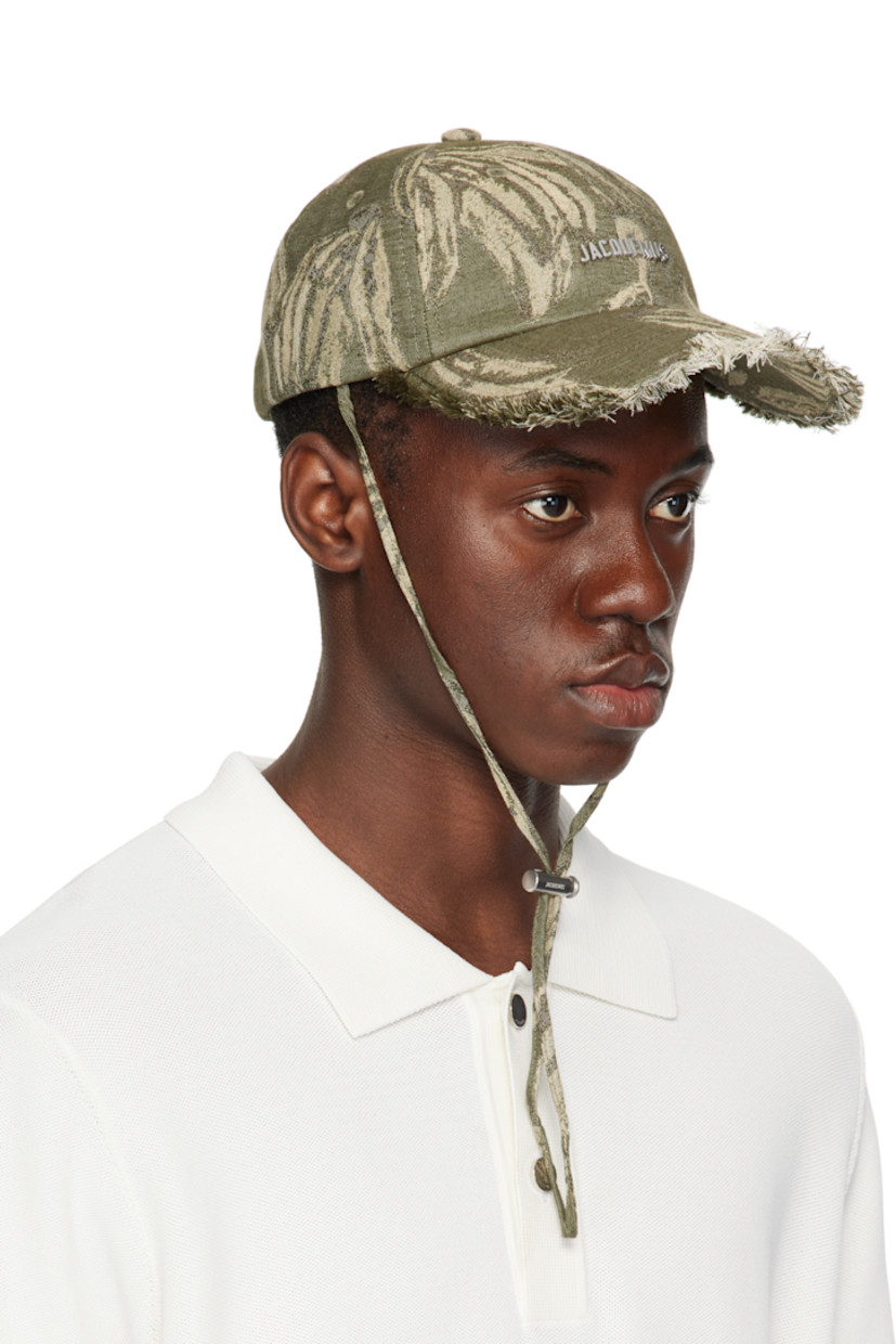 Cotton canvas cap in khaki.

· Jacquard graphic pattern throughout
· Embroidered eyelets at crown
· Logo hardware at face
· Frayed edge at curved brim
· Cord-lock chin strap
· Cinch fastening
· Logo-engraved silver-tone hardware

Supplier color: Jacquard banana logo/Khaki