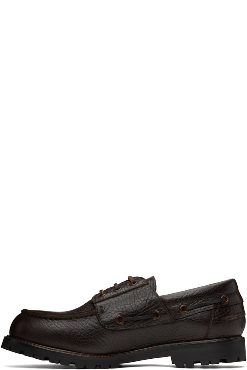 Grained leather boat shoes in brown.

· Moc toe
· Lace-up closure
· Lace-up detailing at padded collar
· Pinched seam at heel counter
· Buffed leather lining
· Topstitching at welt
· Treaded Vibram® rubber sole

Supplier color: Conker
