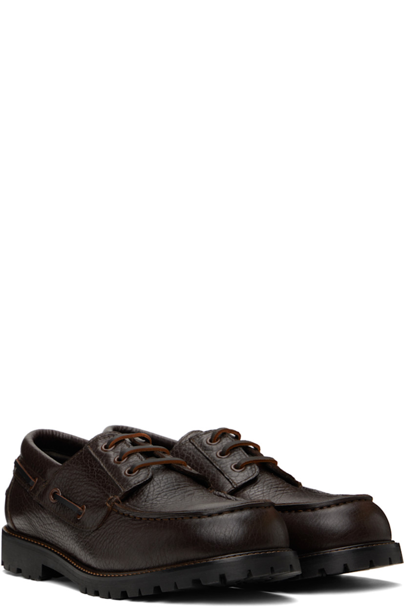 Grained leather boat shoes in brown.

· Moc toe
· Lace-up closure
· Lace-up detailing at padded collar
· Pinched seam at heel counter
· Buffed leather lining
· Topstitching at welt
· Treaded Vibram® rubber sole

Supplier color: Conker