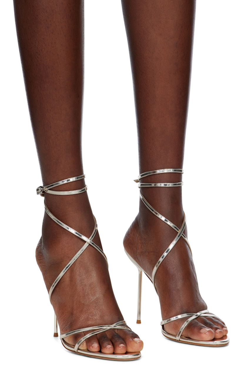Patent leather heeled sandals in gold tone. 

· Open toe
· Crisscrossing straps at vamp
· Wraparound pin-buckle ankle strap
· Logo embossed at leather footbed
· Covered stiletto heel with rubber injection
· Leather sole
· Heel: H4.5"

Supplier color: Gold