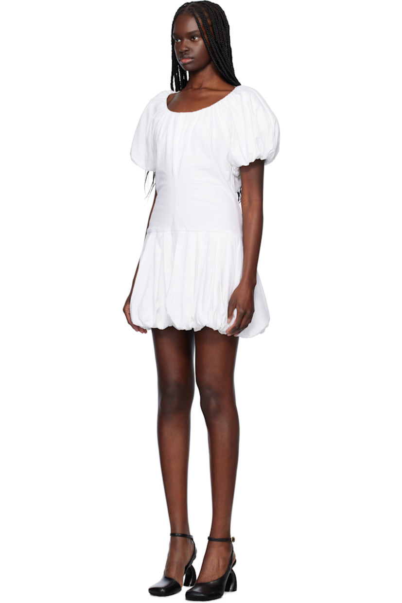 Cotton jersey minidress. Gathering and draping throughout. 

· Scoop neck
· Detachable faux-leather cinch belt 
· Pleats at dropped waist
· Bubble hem
· Padded shoulders 
· Elasticized puff sleeves
· Self-tie fastening at low back

Supplier color: White