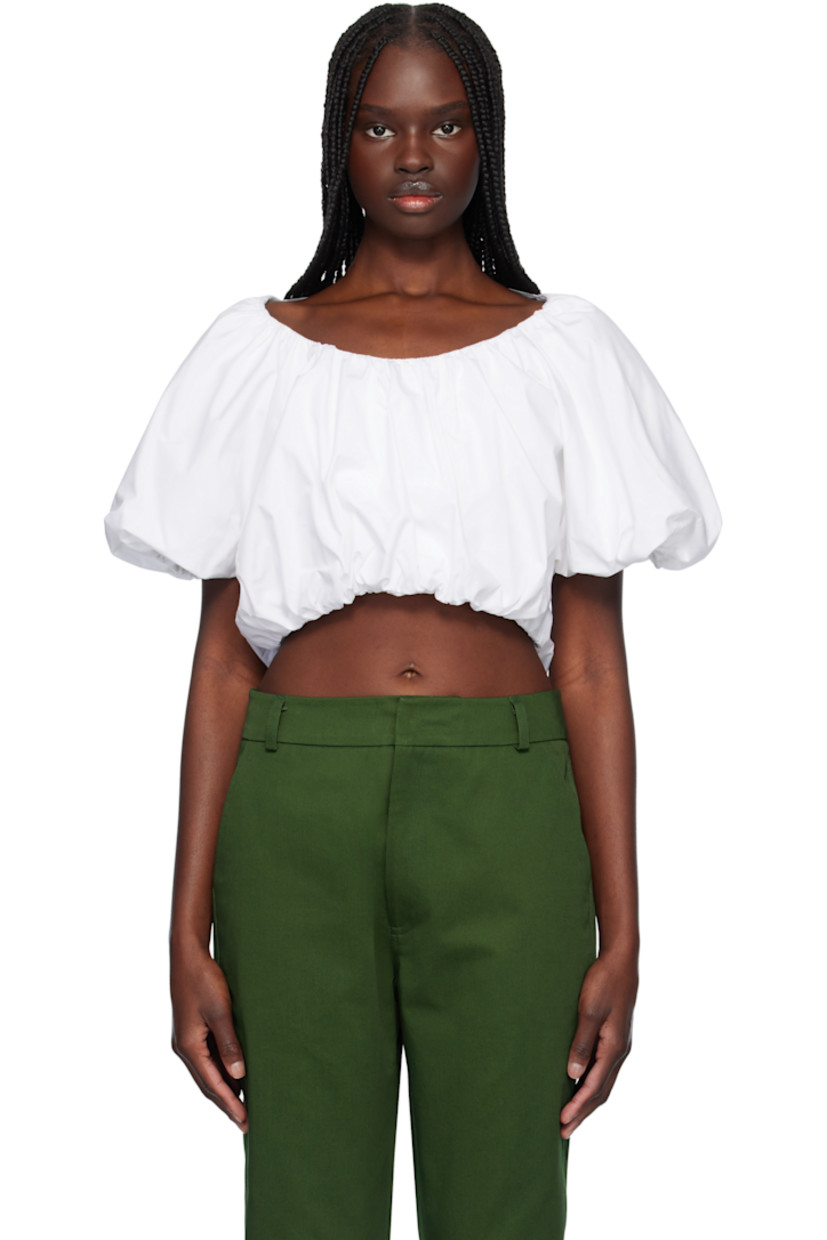 Cotton poplin top. Gathering throughout. 

· Boat neck
· Elasticized cropped hem and cuffs
· Padded shoulders
· Puff sleeves
· Self-tie fastening at low back

Supplier color: White