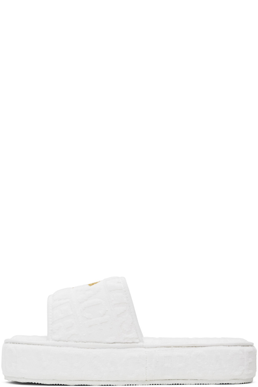 Cotton terrycloth slippers in white.

· Logo pattern flocked throughout
· Open toe
· Logo-embroidered velcro strap at vamp
· Covered platform midsole
· Treaded rubber outsole
· Platform: H2"

Supplier color: White