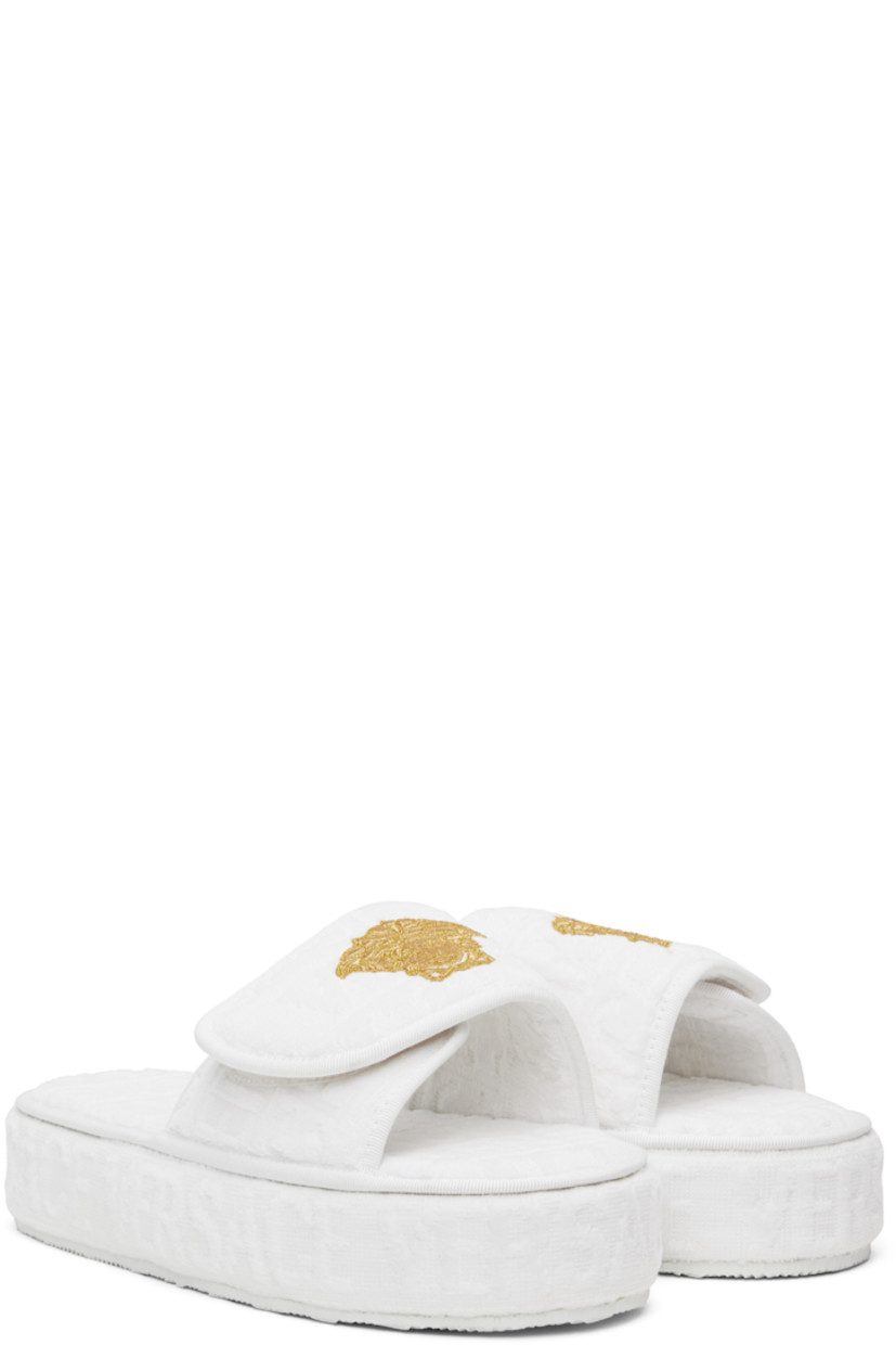 Cotton terrycloth slippers in white.

· Logo pattern flocked throughout
· Open toe
· Logo-embroidered velcro strap at vamp
· Covered platform midsole
· Treaded rubber outsole
· Platform: H2"

Supplier color: White
