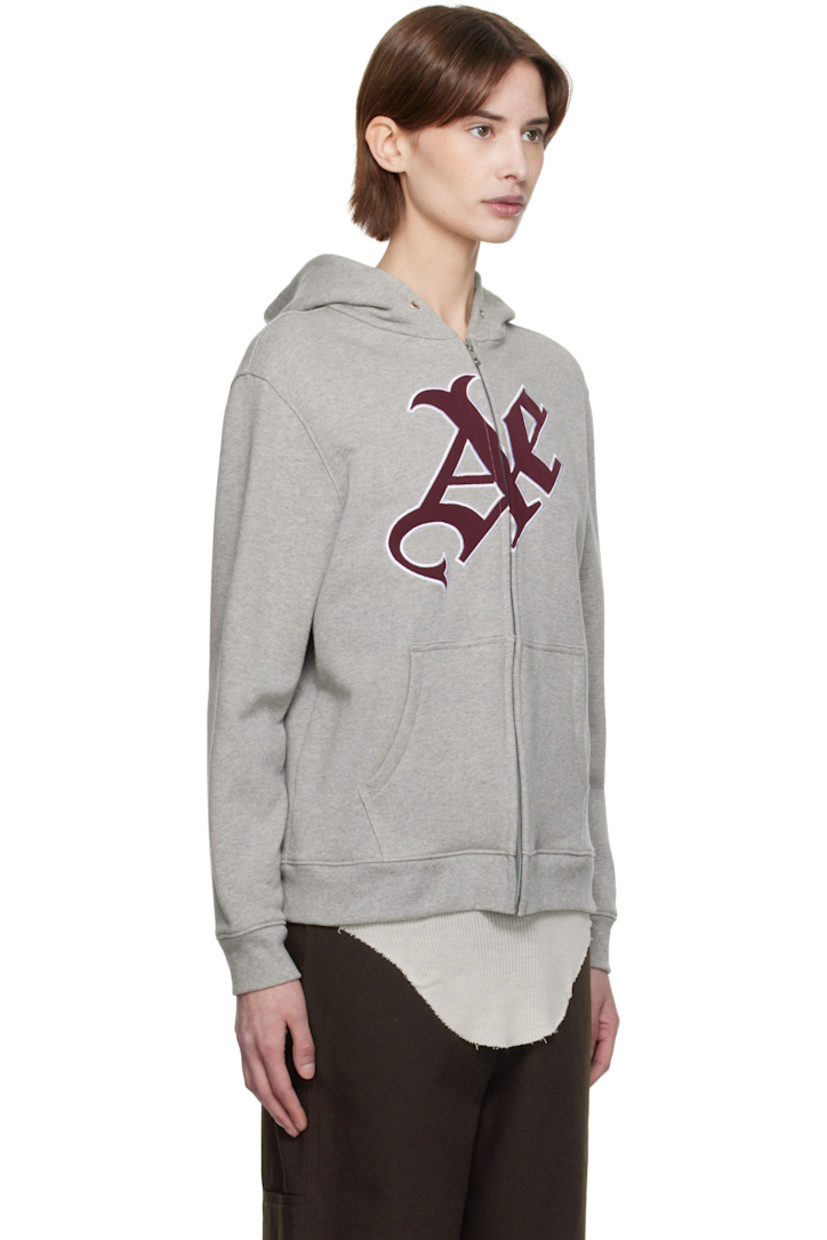 French terry hoodie.

· Eyelets at hood
· Zip closure
· Padded satin logo appliqué at front
· Patch pockets
· Rib-knit hem and cuffs

Supplier color: Grey