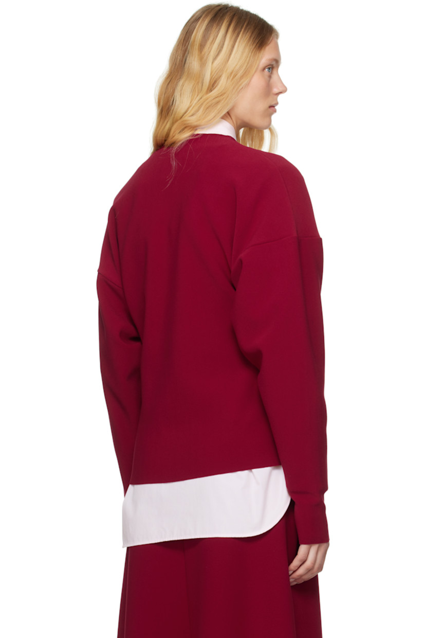 Double-faced stretch polyester bonded crêpe cardigan. Raw edges throughout. 

· Round neck
· Button closure
· Dropped shoulders 

Supplier color: Ruby