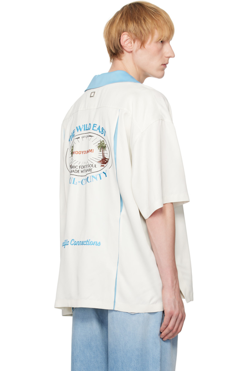 Viscose satin shirt.

· Open spread collar
· Button closure
· Logo embroidered at chest
· Patch pocket
· Logo patch at hem
· Dropped shoulders
· Vented side seams
· Logo hardware at back collar
· Twin pleats at back yoke
· Logo, graphic, and text embroidered at back

Supplier color: Ivory