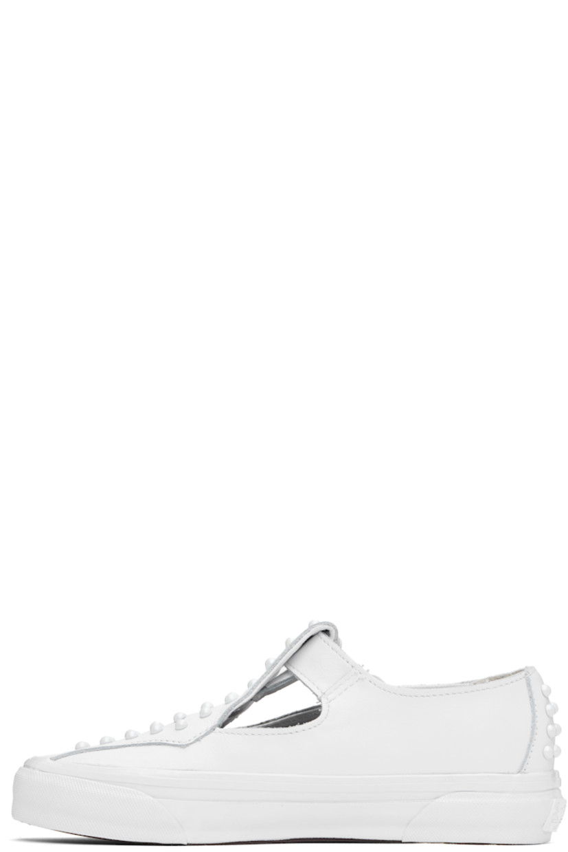 Low-top buffed leather Mary Jane-style sneakers in white.

· Studs at vamp and heel counter
· Cutouts and pin-buckle strap at vamp
· Logo flag at outer side 
· Logo patch at heel
· Canvas lining 
· Treaded rubber sole

Supplier color: Pearlized white