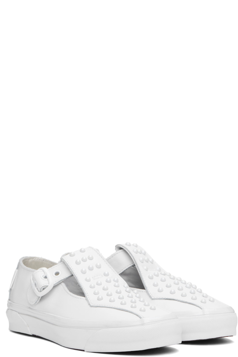 Low-top buffed leather Mary Jane-style sneakers in white.

· Studs at vamp and heel counter
· Cutouts and pin-buckle strap at vamp
· Logo flag at outer side 
· Logo patch at heel
· Canvas lining 
· Treaded rubber sole

Supplier color: Pearlized white