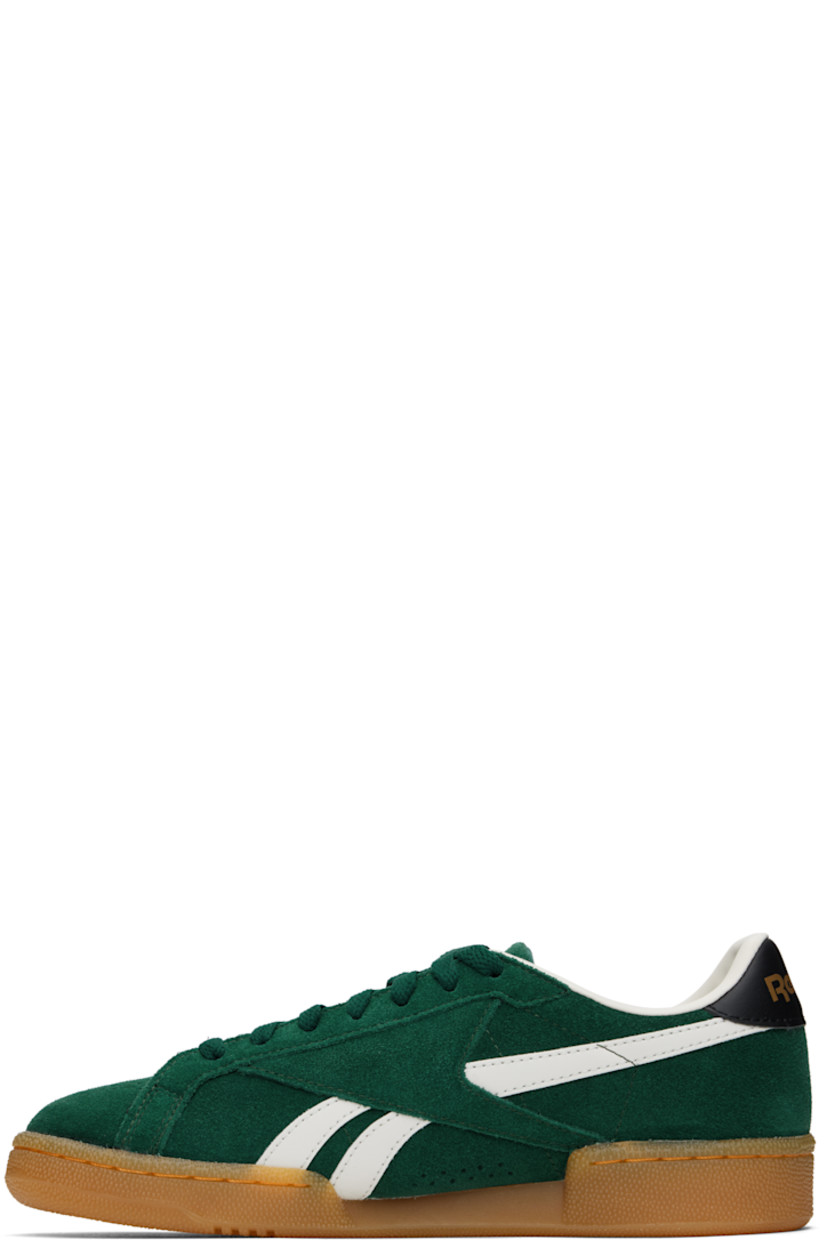 Low-top suede sneakers in green.

· Buffed leather trim throughout
· Perforations at toe
· Lace-up closure
· Logo embossed at padded tongue
· Padded collar
· Signature stripes at sides
· Inset logo patch at outer side
· Logo stamp at heel tab
· Buffed leather and mesh lining
· Treaded rubber sole

Supplier color: Collegiategreen/Black/Gum