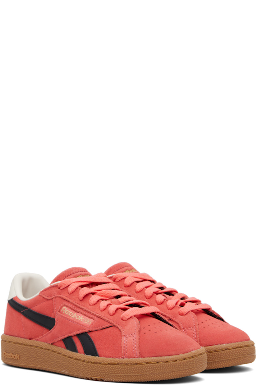 Low-top suede sneakers in pink.

· Perforated detailing at toe
· Lace-up closure
· Logo embossed at padded tongue
· Padded collar
· Inset logo patch at outer side
· Signature stripes at sides
· Logo printed at heel tab
· Mesh and grained leather lining
· Treaded rubber sole

Supplier color: Sunsetcoral/Black/Gum