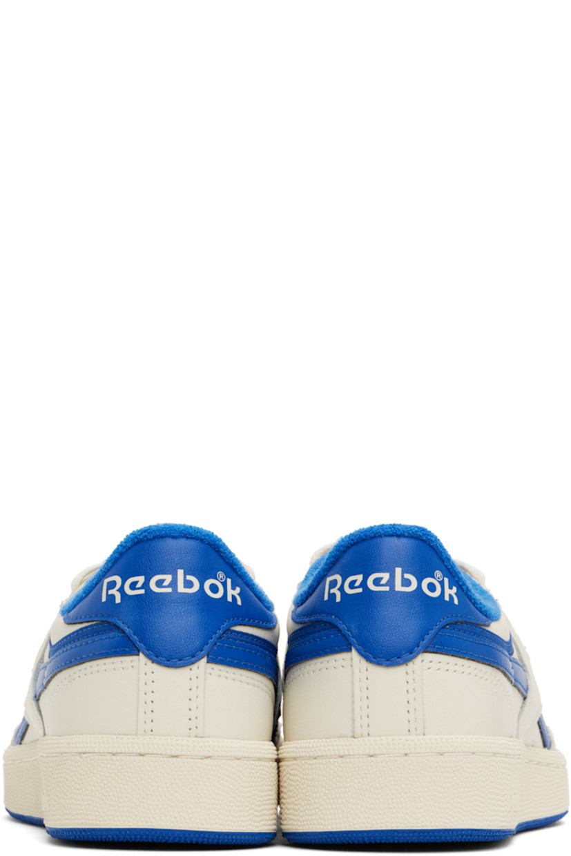 Low-top buffed leather sneakers in off-white and blue.

· Suede trim at toe
· Perforated detailing at vamp
· Lace-up closure
· Logo patch at padded tongue
· Padded collar
· Inset logo patch at outer side
· Signature stripes at sides
· Logo printed at heel tab
· Terry cloth lining
· Treaded rubber sole

Supplier color: Chalk/Croyal/Excred