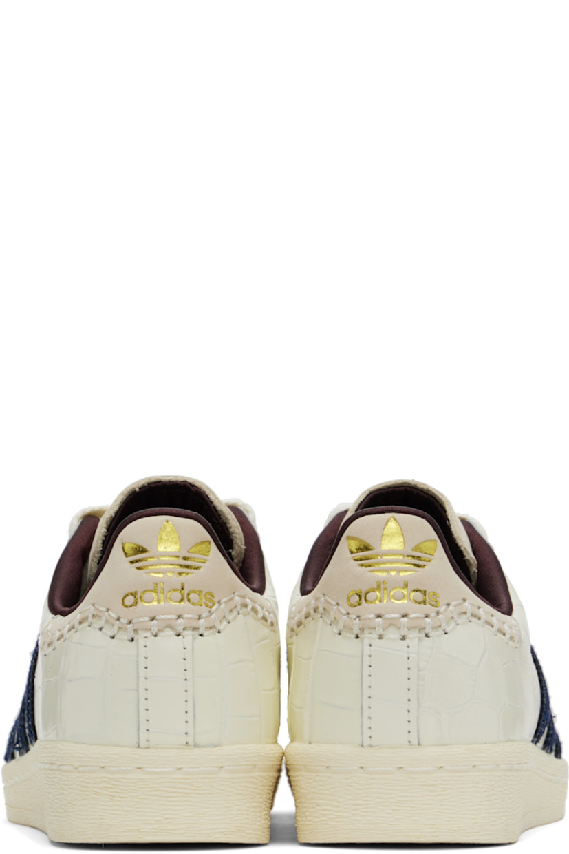 Low-top croc-embossed leather sneakers in white. 

· Textured rubber cap toe
· Lace-up closure
· Logo embossed at padded suede tongue
· Padded collar
· Serrated signature stripes and perforations at sides
· Logo stamp at outer side
· Blanket stitching and logo embossed at suede heel tab
· Satin lining
· Treaded rubber sole

Part of the Wales Bonner x adidas Originals collaboration.

Supplier color: Wonder white/Collegiate navy/Night red