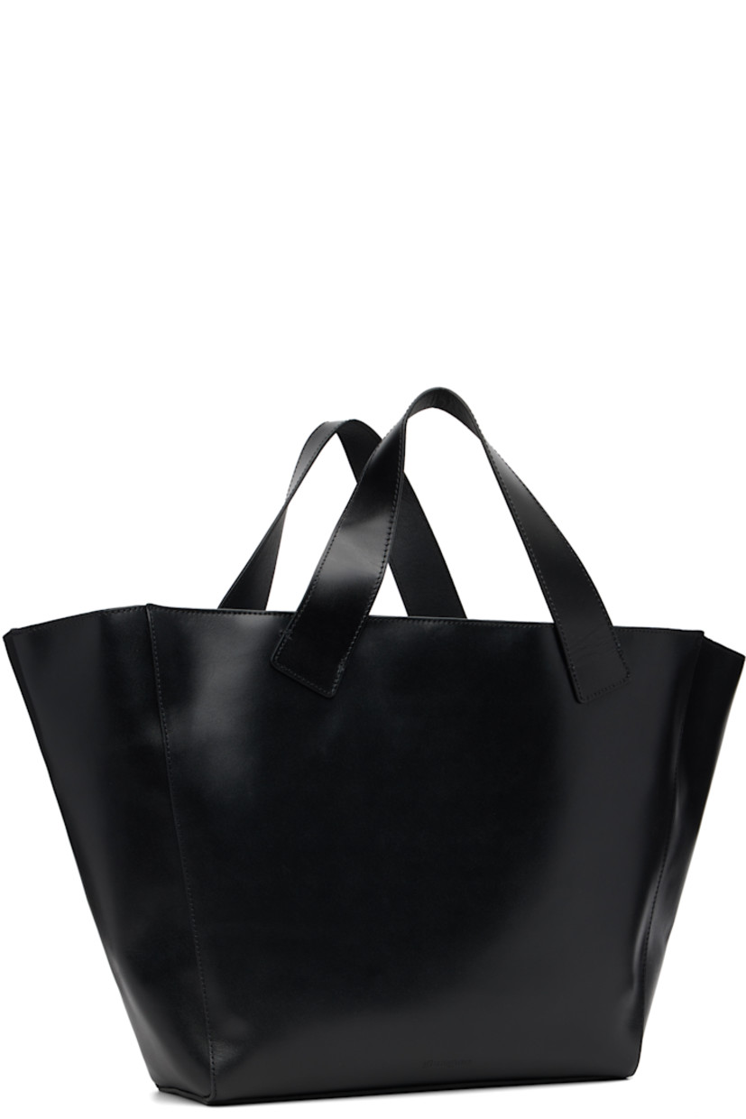 Buffed leather tote.

· Fixed carry handles
· Pin-buckle strap and studs at face
· Magnetic closure
· Patch pocket at interior
· Suede lining
· H12" x W21" x D4"

Supplier color: Black