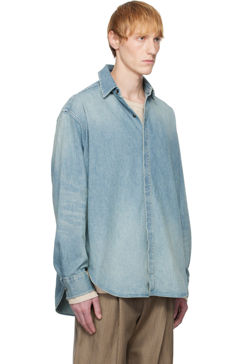 Non-stretch denim shirt. Fading throughout. 

· Spread collar
· Concealed button closure
· Shirttail hem 
· Buttoned barrel cuffs
· Rubberized logo patch at back collar 
· Twin pleats at back yoke
· Horn hardware

Supplier color: Medium indigo