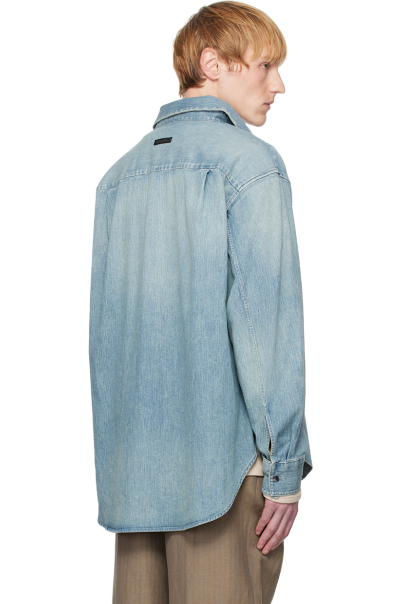 Non-stretch denim shirt. Fading throughout. 

· Spread collar
· Concealed button closure
· Shirttail hem 
· Buttoned barrel cuffs
· Rubberized logo patch at back collar 
· Twin pleats at back yoke
· Horn hardware

Supplier color: Medium indigo