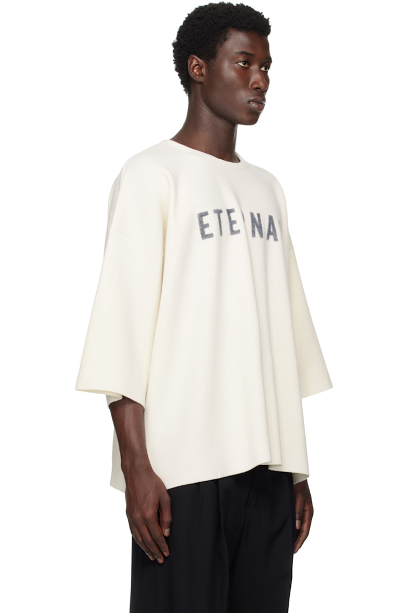 Knit virgin wool short-sleeve sweater.

· Flocked text at front 
· Raw edge at hem and cuffs
· Dropped shoulders 
· Rubberized logo patch at back 

Supplier color: Off white/Black