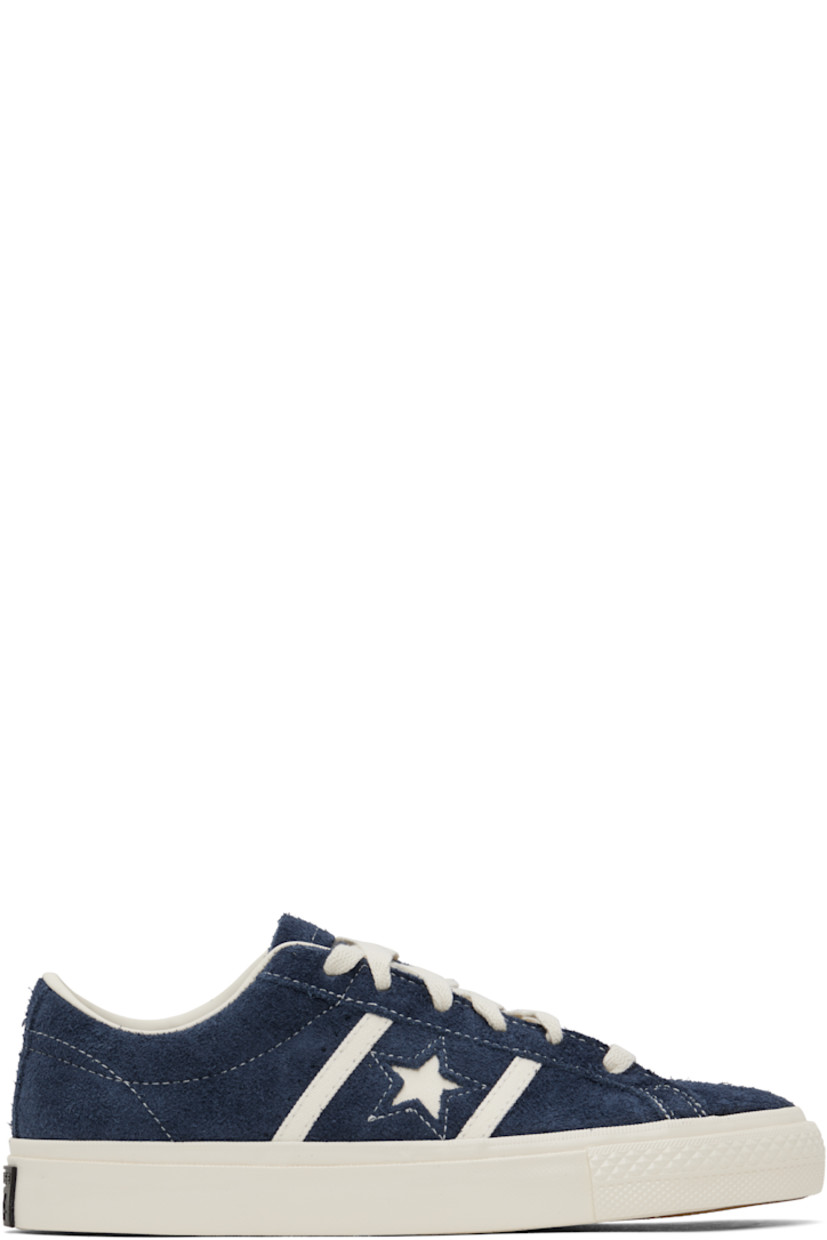 Low-top suede sneakers in navy.

· Lace-up closure
· Logo embossed at tongue
· Concealed elasticized gussets at tongue
· Padded collar
· Logo cutout at sides
· Perforations and canvas trim
· Rubberized logo patch at heel
· Cushioned CX foam footbed
· Buffed leather and canvas lining
· Treaded rubber sole

Supplier color: Navy/Egret/Egret