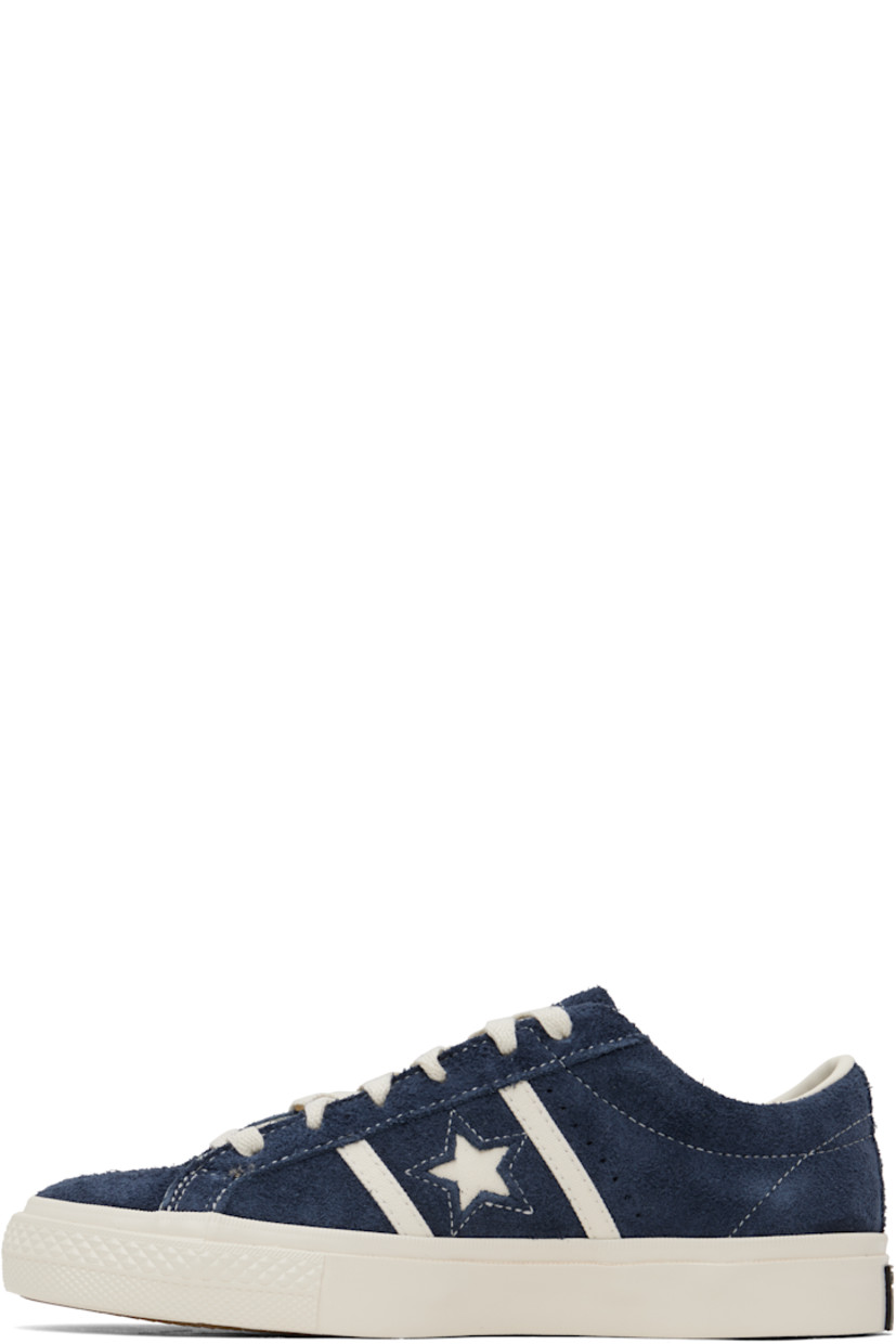Low-top suede sneakers in navy.

· Lace-up closure
· Logo embossed at tongue
· Concealed elasticized gussets at tongue
· Padded collar
· Logo cutout at sides
· Perforations and canvas trim
· Rubberized logo patch at heel
· Cushioned CX foam footbed
· Buffed leather and canvas lining
· Treaded rubber sole

Supplier color: Navy/Egret/Egret