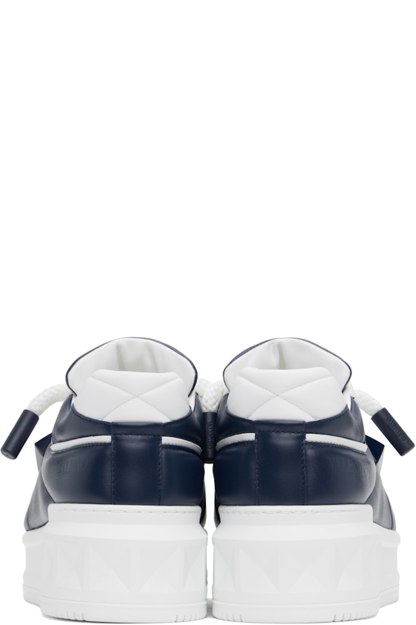 Low-top buffed calfskin sneakers in white and navy.

· Perforated detailing throughout
· Lace-up closure
· Padded tongue and collar
· Concealed elasticized gussets at tongue
· Logo printed at tongue and outer side
· Signature pyramid stud at outer side
· Quilted heel tab
· Buffed leather lining
· Logo-embossed treaded rubber platform sole
· Platform: H1.75"

Supplier color: Bianco/Worker