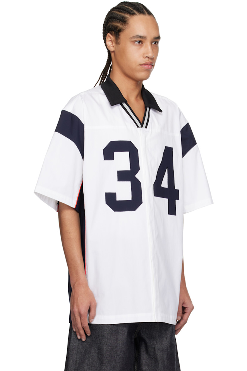 Cotton canvas shirt.

· Rib-knit spread collar
· Striped open placket
· Concealed button closure
· Text appliqués at front
· Piping at side seams and sleeves
· Vented side seams

Supplier color: White