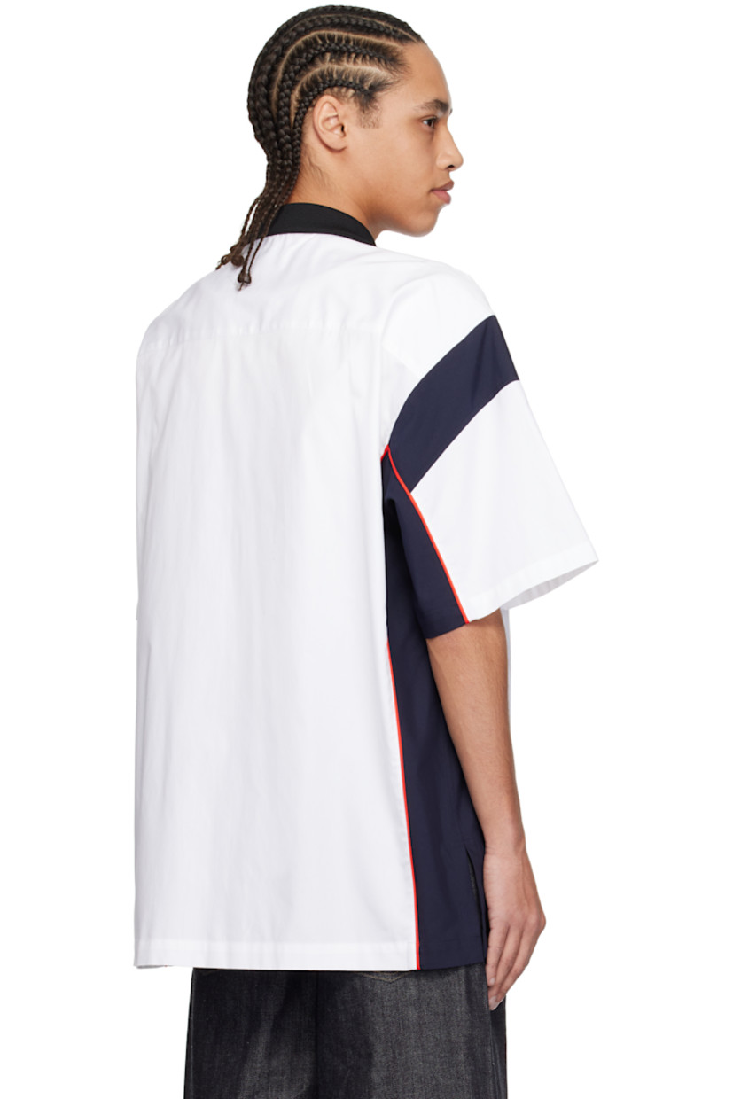 Cotton canvas shirt.

· Rib-knit spread collar
· Striped open placket
· Concealed button closure
· Text appliqués at front
· Piping at side seams and sleeves
· Vented side seams

Supplier color: White