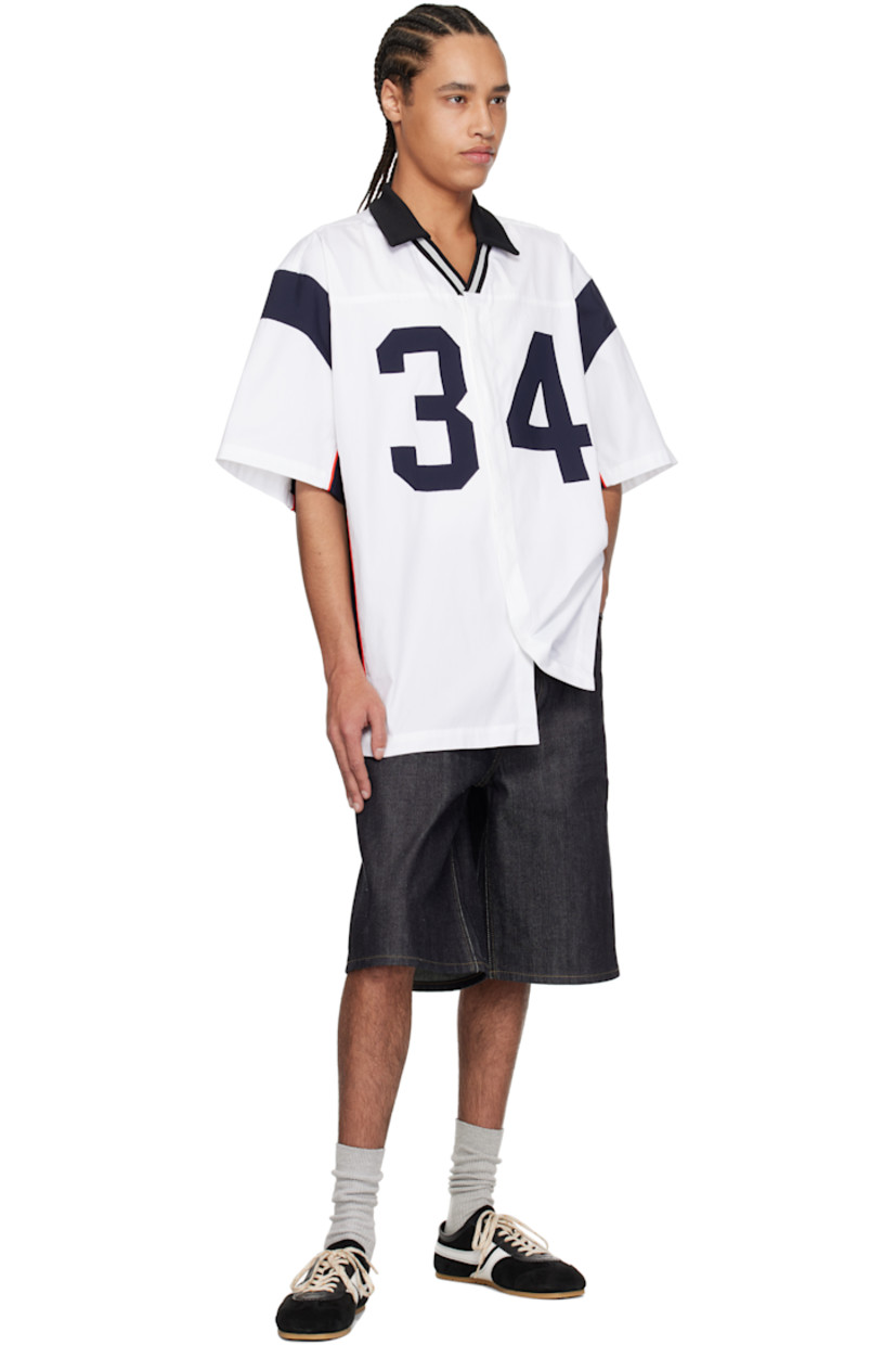 Cotton canvas shirt.

· Rib-knit spread collar
· Striped open placket
· Concealed button closure
· Text appliqués at front
· Piping at side seams and sleeves
· Vented side seams

Supplier color: White