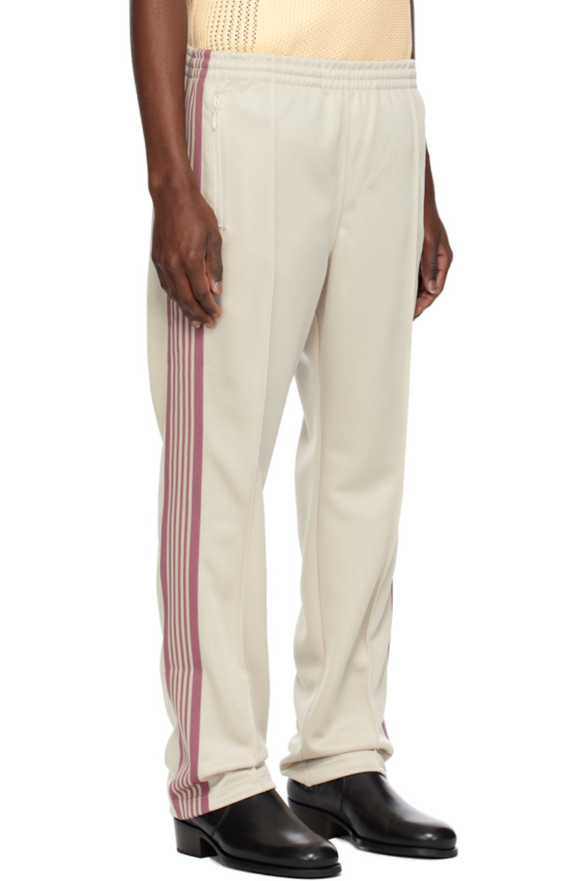 Polyester interlock jersey track pants.

· Concealed drawstring at elasticized waistband
· Three-pocket styling
· Pinched seams and embroidered logo graphic at front
· Striped knit trim at outseams

Supplier color: Ivory