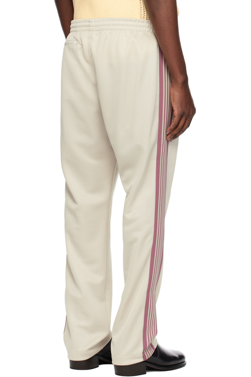 Polyester interlock jersey track pants.

· Concealed drawstring at elasticized waistband
· Three-pocket styling
· Pinched seams and embroidered logo graphic at front
· Striped knit trim at outseams

Supplier color: Ivory