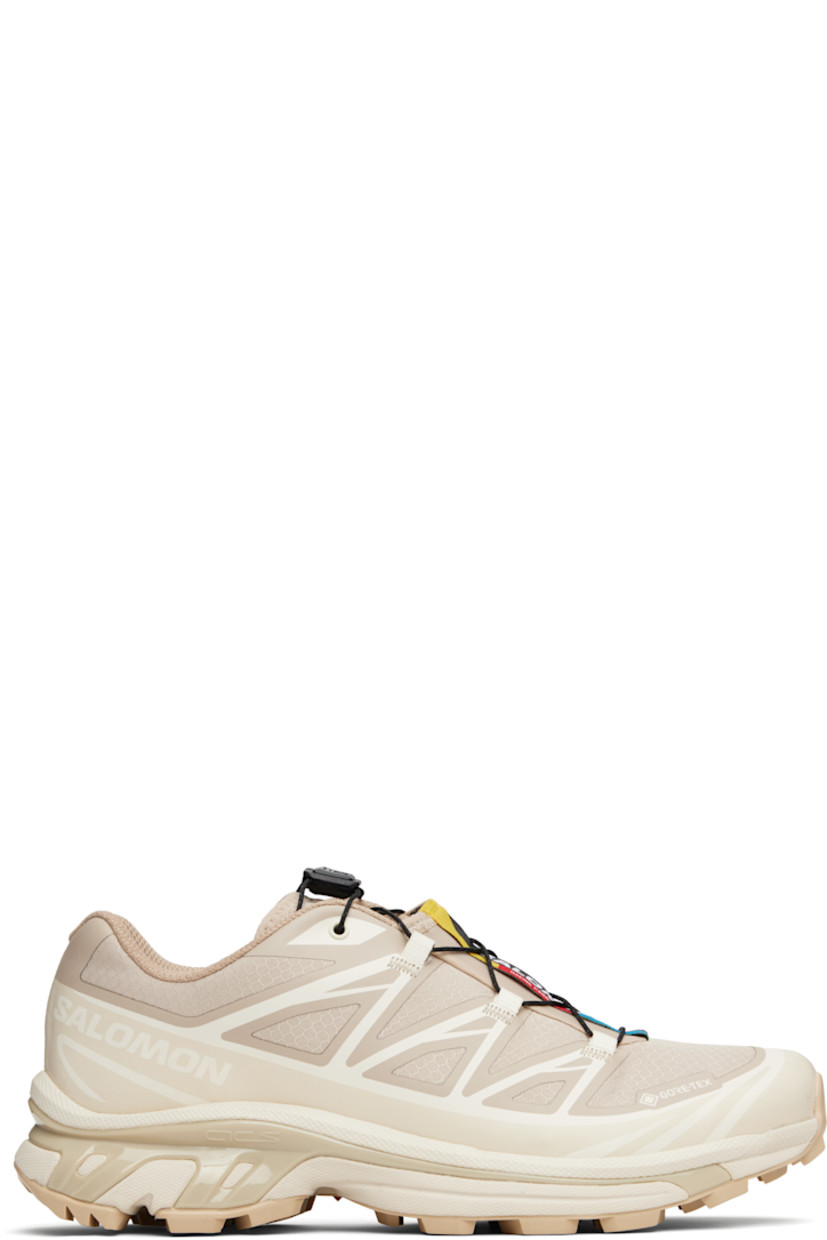 Low-top ripstop sneakers in tan and beige.

· GORE-TEX™ ePE waterproof membrane, PFC-free
· Bonded trim throughout
· Logo embossed at toe
· Quicklace™ closure
· Logo patch at vamp
· Logo-woven pull-loop at padded tongue
· Padded collar
· Bonded sensiFIT™ panel at sides
· Logo printed at outer side
· Text printed at inner side
· Molded OrthoLite® insole
· Mesh lining
· Agile Chassis™ System at EnergyCell midsole
· Treaded Mud Contagrip® rubber sole

Supplier color: Oxford tan/Almond milk/Safari