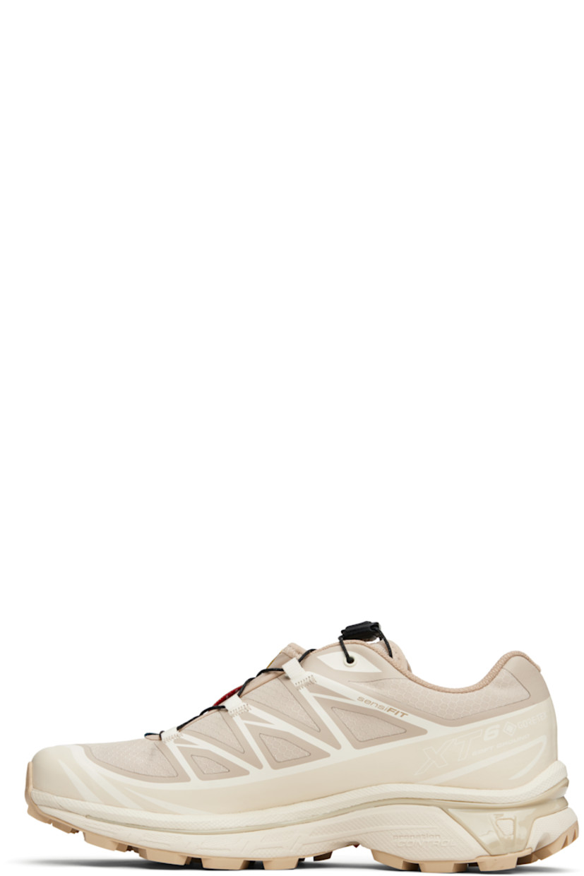 Low-top ripstop sneakers in tan and beige.

· GORE-TEX™ ePE waterproof membrane, PFC-free
· Bonded trim throughout
· Logo embossed at toe
· Quicklace™ closure
· Logo patch at vamp
· Logo-woven pull-loop at padded tongue
· Padded collar
· Bonded sensiFIT™ panel at sides
· Logo printed at outer side
· Text printed at inner side
· Molded OrthoLite® insole
· Mesh lining
· Agile Chassis™ System at EnergyCell midsole
· Treaded Mud Contagrip® rubber sole

Supplier color: Oxford tan/Almond milk/Safari