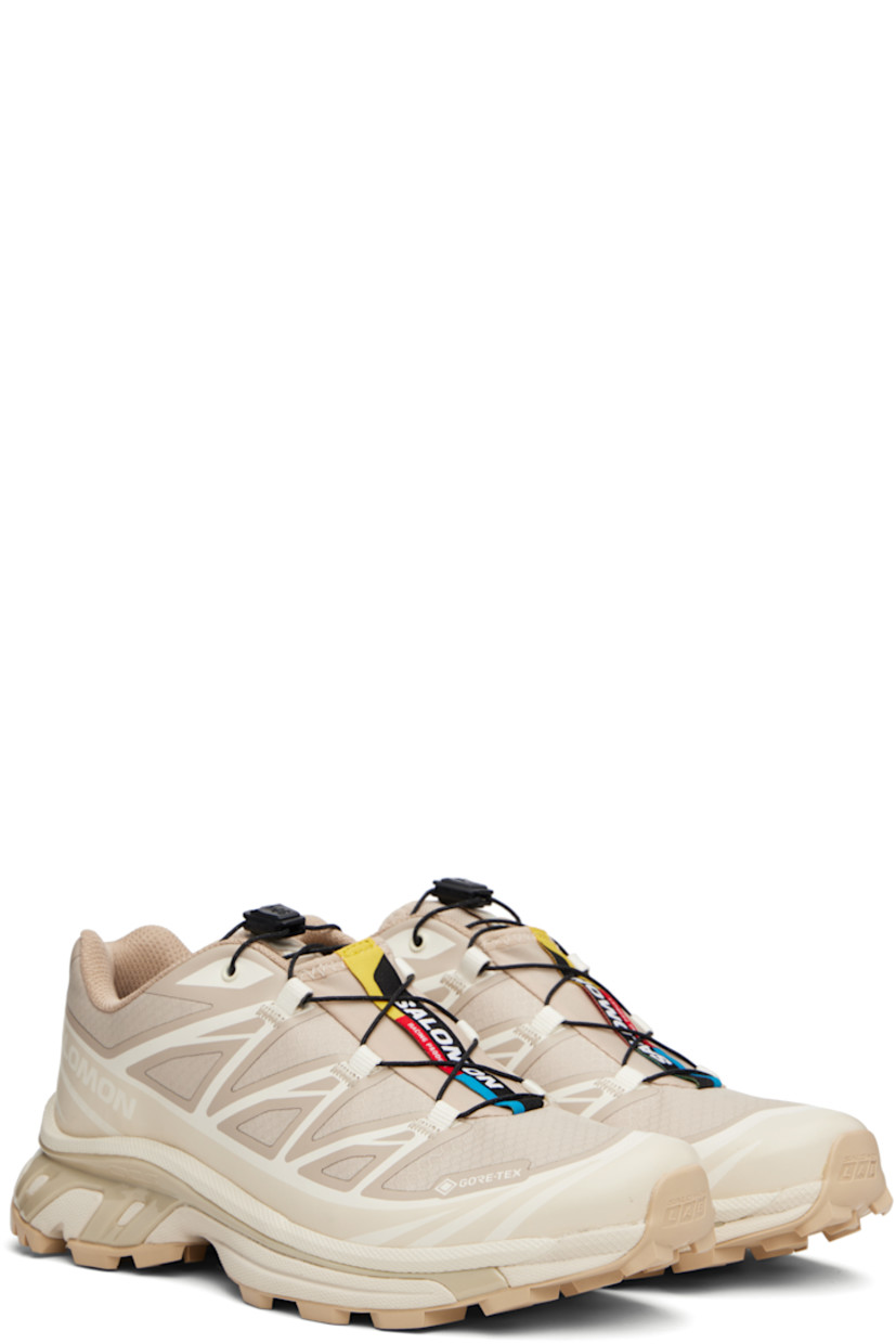 Low-top ripstop sneakers in tan and beige.

· GORE-TEX™ ePE waterproof membrane, PFC-free
· Bonded trim throughout
· Logo embossed at toe
· Quicklace™ closure
· Logo patch at vamp
· Logo-woven pull-loop at padded tongue
· Padded collar
· Bonded sensiFIT™ panel at sides
· Logo printed at outer side
· Text printed at inner side
· Molded OrthoLite® insole
· Mesh lining
· Agile Chassis™ System at EnergyCell midsole
· Treaded Mud Contagrip® rubber sole

Supplier color: Oxford tan/Almond milk/Safari