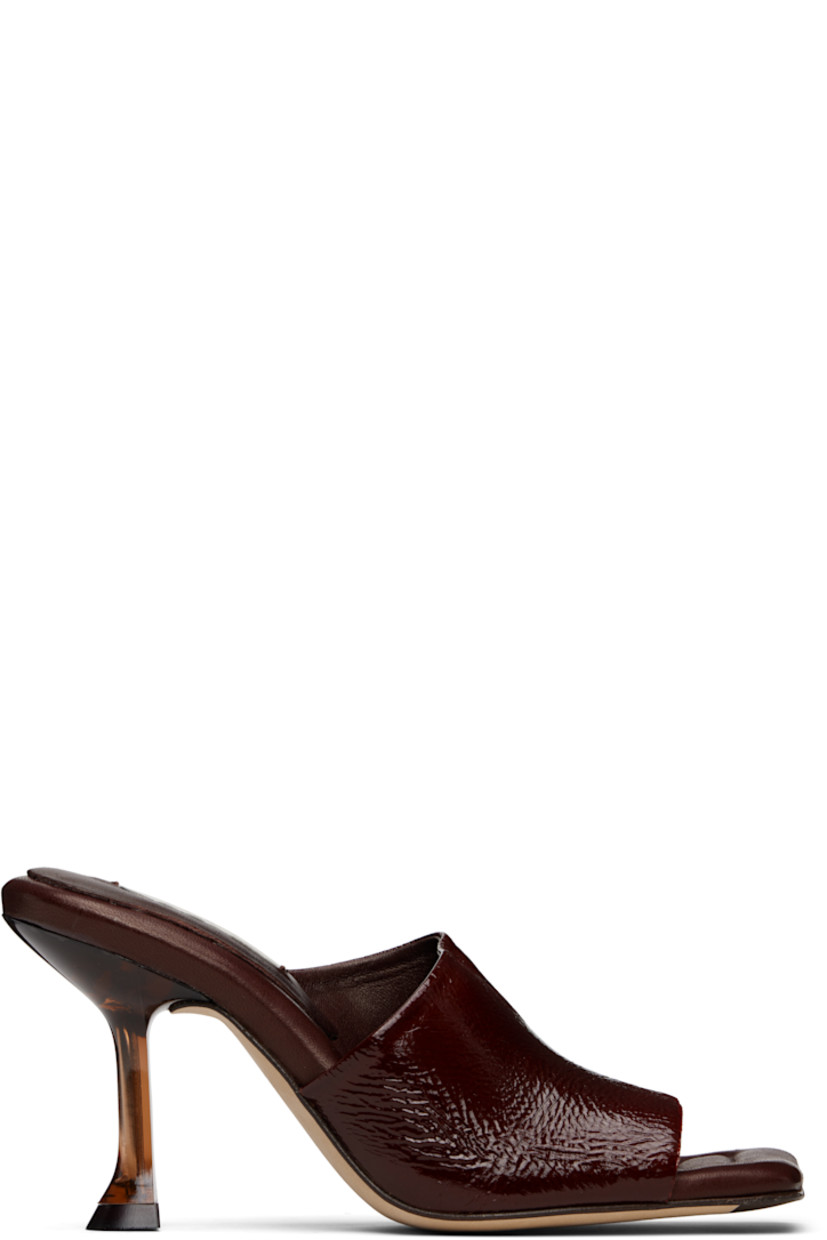 Brushed suede mules.

· Open square toe 
· Strap at vamp
· Logo patch at padded leather footbed
· Semi-transparent spool heel
· Suede sole with rubber injection
· Heel: H3.25"

Supplier color: Brown