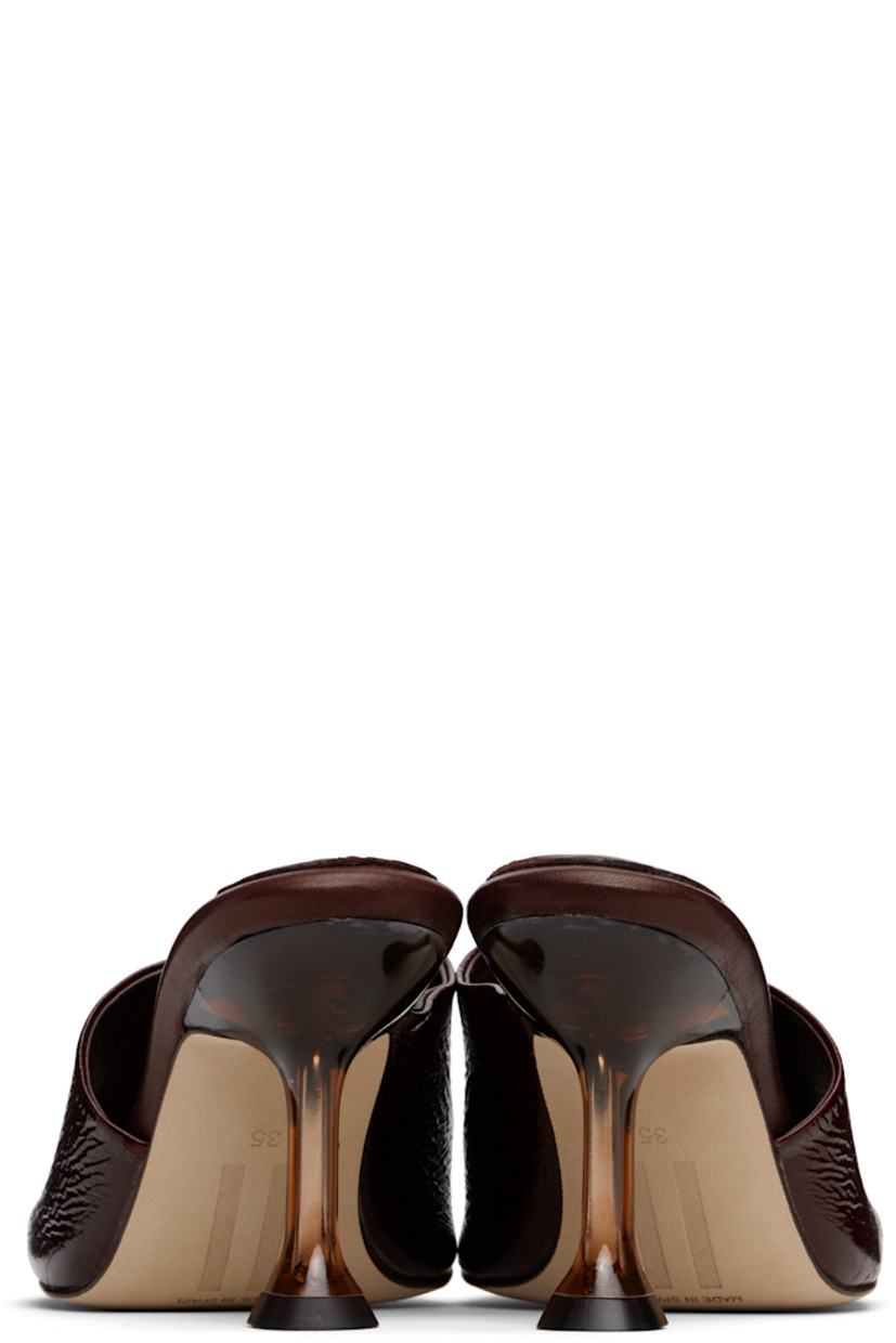 Brushed suede mules.

· Open square toe 
· Strap at vamp
· Logo patch at padded leather footbed
· Semi-transparent spool heel
· Suede sole with rubber injection
· Heel: H3.25"

Supplier color: Brown