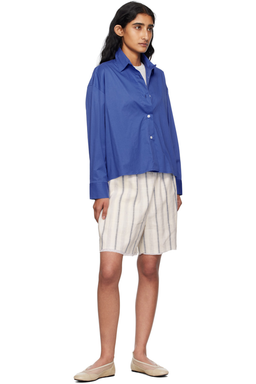 Stretch organic cotton poplin shirt.

· Certified OEKO-TEX® Standard 100
· Spread collar
· Button closure
· Cropped droptail hem 
· Dropped shoulders
· Buttoned barrel cuffs
· Twin pleats at back yoke 
· Logo-engraved hardware

Supplier color: Hortensia